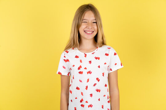 Coquettish beautiful kid girl smiling happily, blinking at camera in a playful manner, flirting with you.