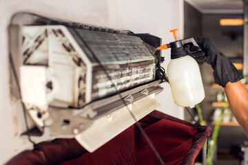  Cleaning the air conditioner by spraying. man washes off a special foam for cleaning air...