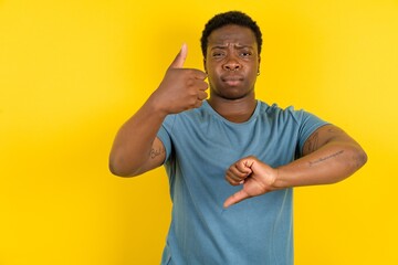 young handsome man showing thumbs up and thumbs down, difficult choose concept - obrazy, fototapety, plakaty