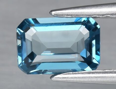 Natural gemstone blue topaz on a gray background