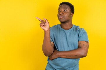 Photo of attractive Young handsome man standing over yellow studio background direct finger empty...