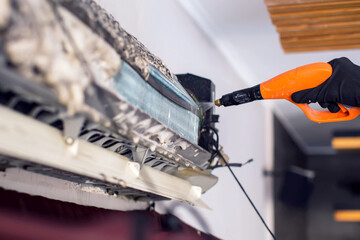  Cleaning the air conditioner by spraying. man washes off a special foam for cleaning air...