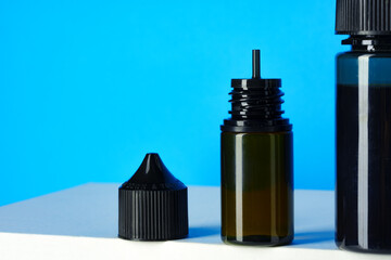 Black electronic cigarettes liquid bottles on blue background