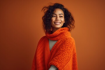 Studio shot of a woman wrapped in a cozy sweater against a gradient orange background - Autumn Warmth - AI Generated