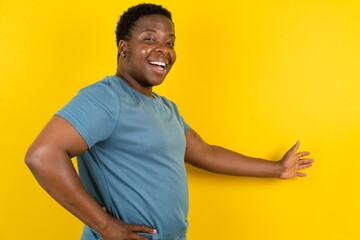 Young handsome man standing over yellow studio background feeling happy and cheerful, smiling and...