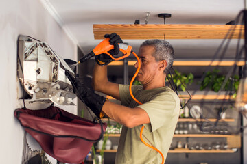  Cleaning the air conditioner by spraying. man washes off a special foam for cleaning air...