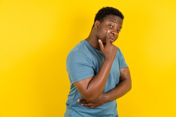Young handsome man standing over yellow studio background Pointing to the eye watching you gesture,...