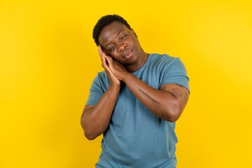 Young handsome man standing over yellow studio background sleeping tired dreaming and posing with...