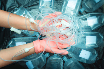 Hands of a female officer sorting toxic waste, saline bottles Syringes, from clinics or hospitals...