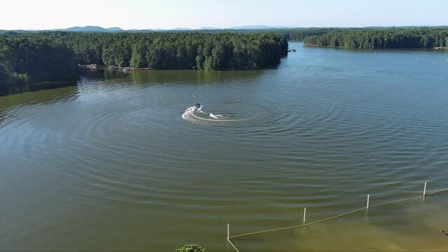 aerial footage of a gorgeous summer landscape at Proctor Landing park with green lake water, trees and grass, boats and people in the water with blue sky and clouds at Lake Acworth in Acworth Georgia