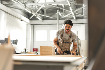 Young man doing woodwork in carpentry factory