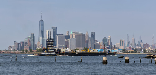 barge passing in front of downtown manhattan skyline in new york city (hudson river cityscape)...