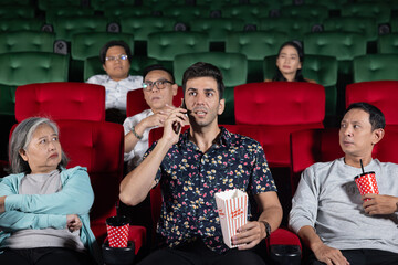 Caucasian guy using smartphone in the theatre disturbed other audience