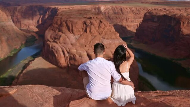 Happy couple on the edge of the cliff at Horseshoe Band Canyon in Paje, Arizona. Adventure and tourism concept. Beautiful nature in USA