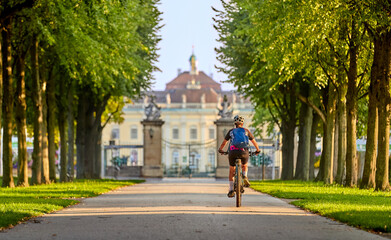 attractive senior woman cycling with her electric mountain bike in an old avenue in Ludwigsburg,...