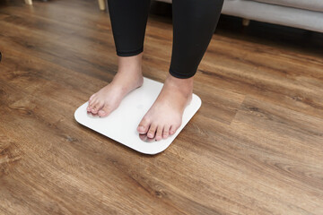Fat diet and scale feet standing on electronic scales for weight control. Measurement instrument in...
