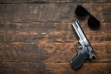 Toy gun and sunglasses on the detective wooden table flatlay background concept. Secret service....