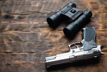 Toy gun and binoculars on the detective wooden table flatlay background concept. Secret service....