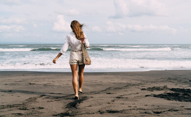 Carefree woman walking towards waving sea