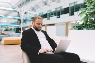Focused businessman working on laptop in spacious hall