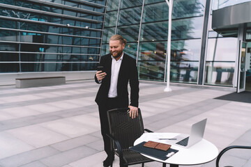 Fototapeta premium Cheerful man blogging on website on smartphone