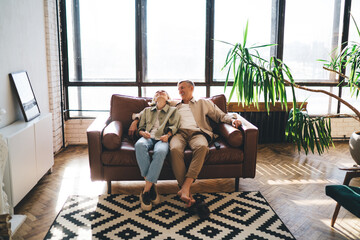 Cheerful senior couple resting on couch in living room