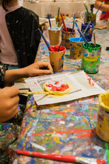 Children enjoy painting in art class, with dirty hands and smocks full of paint.
