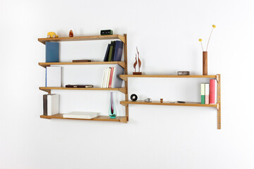 A used midcentury bookshelf original from the 60s mounted on a white wall. Filled with books and...