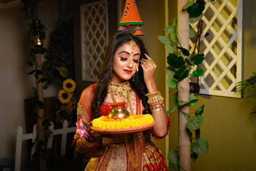 Portrait of pretty young Indian girl wearing traditional saree, gold jewellery and bangles holding...
