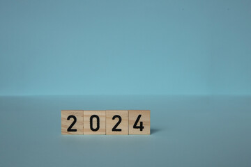 New Year 2024. Wooden blocks date 2024 on blue background . concepts of achieving goals, plan, strategy, new ideas.