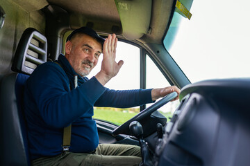 Truck driver saw someone that he knows on the road and he is waving at him.