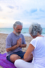Woman and man meditating together sitting facing each other in prayer pose, promoting good personal relationship