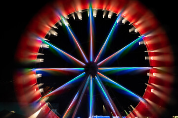 modern ferris wheel with closed cabins at carnival with blue sky no clouds in the background...