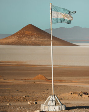 argentinian flag in the salar de arizaro with the cono de arita in the background over the salt flats in the argentinian puna in the north of argentina