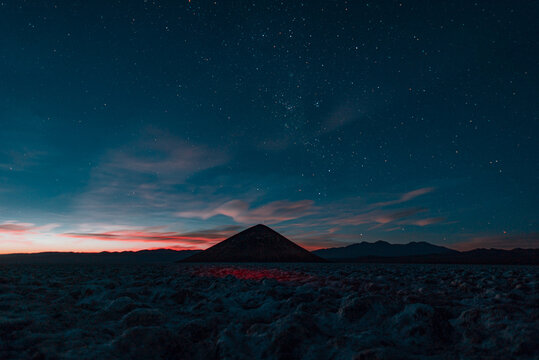 sunset in the high lands in argentina, salar de arizaro and the cono de arita, the most hight and perfect natural pyramid in the world, with the sky full of stars and the galaxy at sight