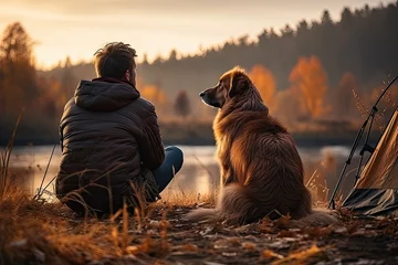 Fotobehang Lonely man sits with faithful dog at tent on riverbank in autumn forest © sommersby