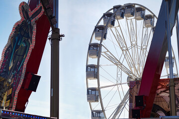 modern ferris wheel with closed cabins at carnival with blue sky no clouds in the background...