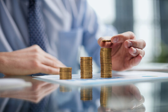 Businessman stacking coins on table, business growth concept. Hand puts coin to stack.