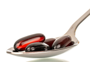 Several medical pills in a metal spoon, macro, isolated on white background.