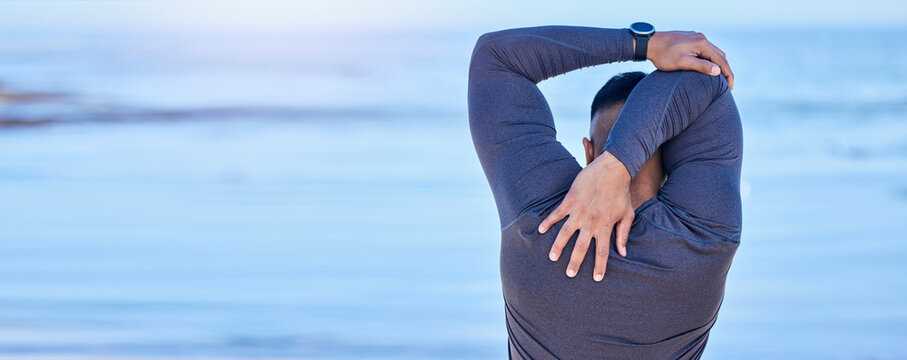 Back, beach and man with fitness, stretching and exercise with warm up, training and cardio sport routine. Person, outdoor or athlete stretch arms, workout and prepare to start activity with wellness