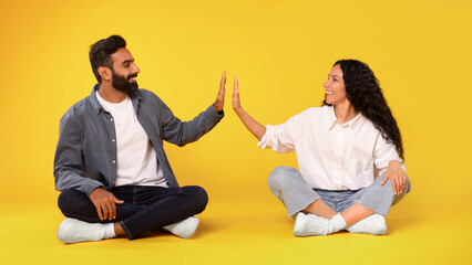 Middle Eastern Spouses Giving High Five Sitting On Yellow Background