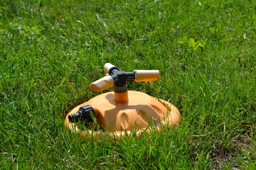 A yellow garden sprinkler lies on the lawn. Yellow garden lawn sprinkler.