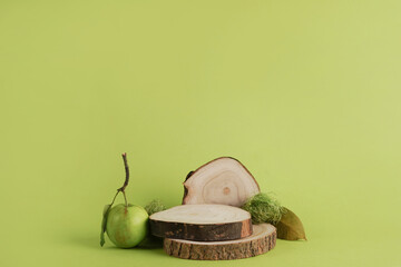 Wooden podium for product on green background. Wood slice and green apple. Concept scene stage showcase for new product, promotion sale, banner, presentation, cosmetic