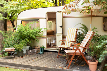 Cozy Campsite on caravan or camper van in forest. Trailer of mobile home stands in garden in...