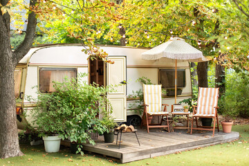 Cozy Campsite on caravan or camper van in forest. Trailer of mobile home stands in garden in...