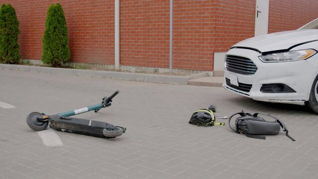 The scene of a road accident between a car and an electric scooter. Footage of a schoolboy hit by a car and his helmet and schoolbag falling to the pavement at an intersection near the school.