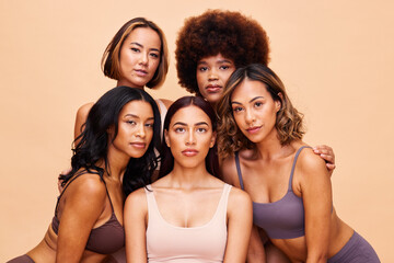 Obraz premium Diversity, beauty and portrait, group of women with self love and solidarity in studio together. Cosmetics on face, power people on beige background with underwear, skincare and makeup for equality.