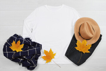 White Sweatshirt mockup. Template blank fall shirt yellow leaves top view on white wooden background. Autumn outfit on wood floor. Woman hoodie clothes. look of today. Female fall accessories
