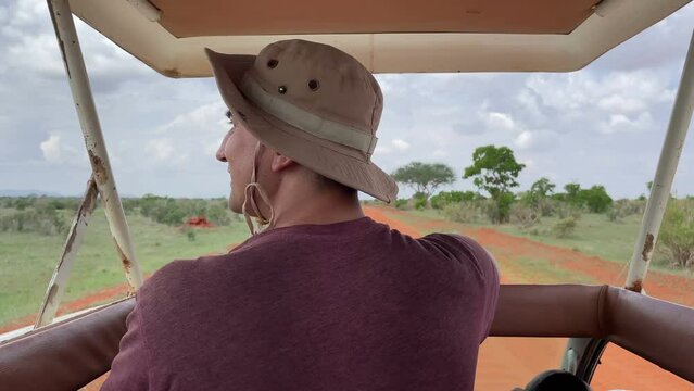 Man travelling on jeep safari tour in Africa national park animal watching driving tourism travel adventures