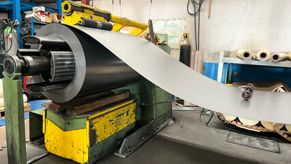 Image of a metal coil in a cutting machine prepared to cut sheets. Metallurgical industry. - obrazy, fototapety, plakaty